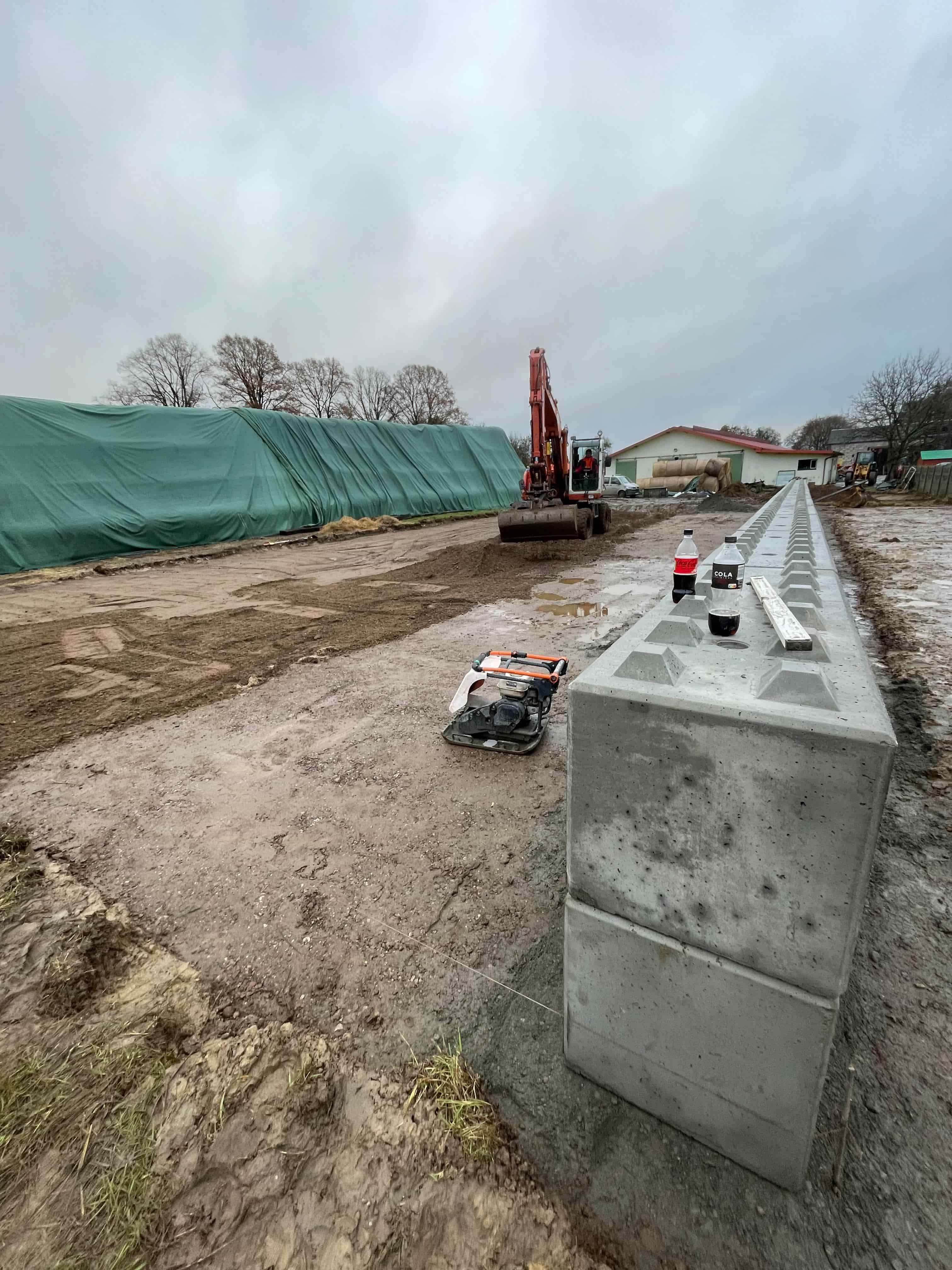 Zdjęcie przedstawia przygotowy teren pod specialną halę. Można zauważyć bloki betonowe tzw. LEGO i koparkę w tle.