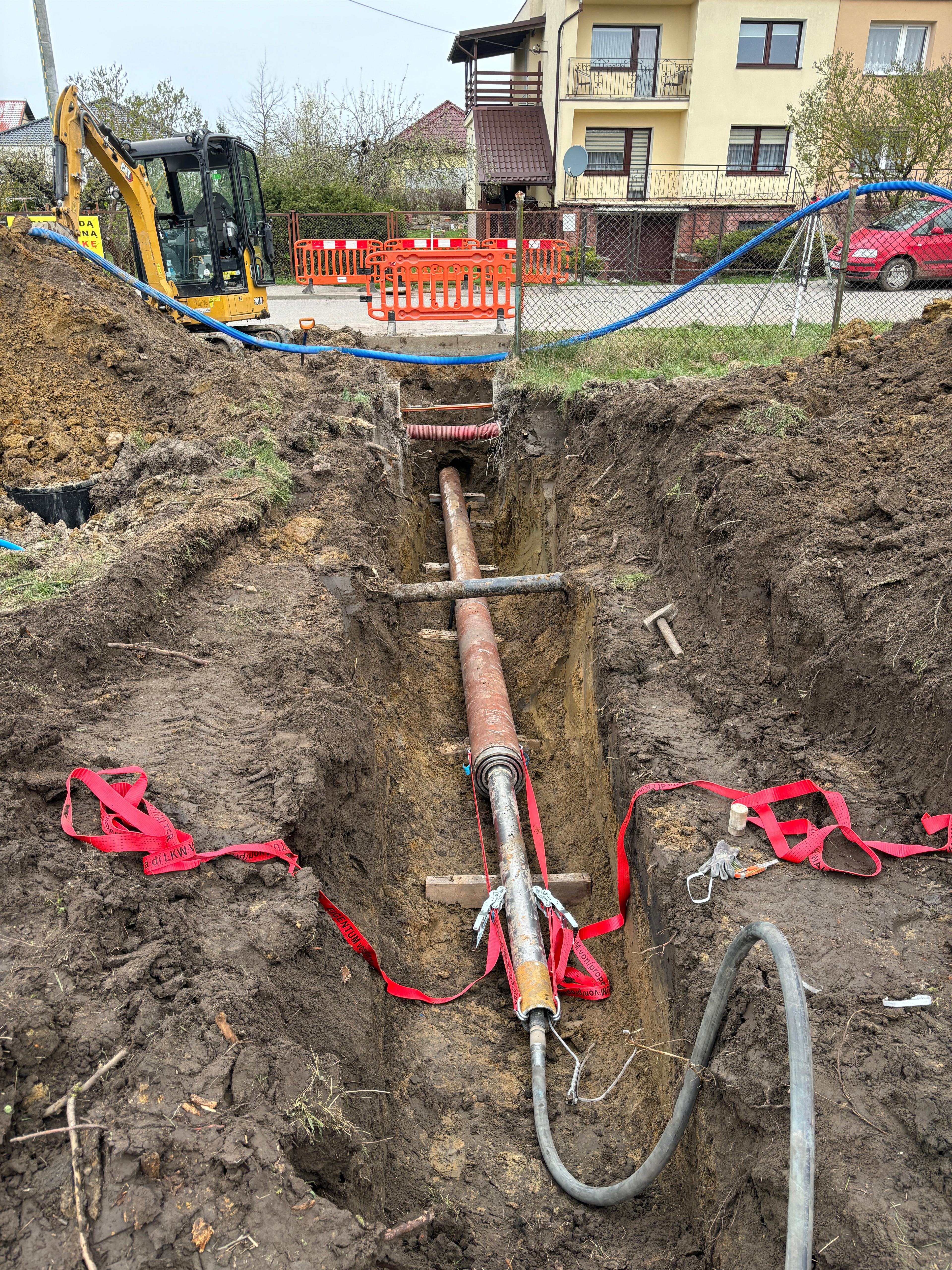 Zdjęcie przedstawia wciskanie rury osłonowej kanalizacyjnej.